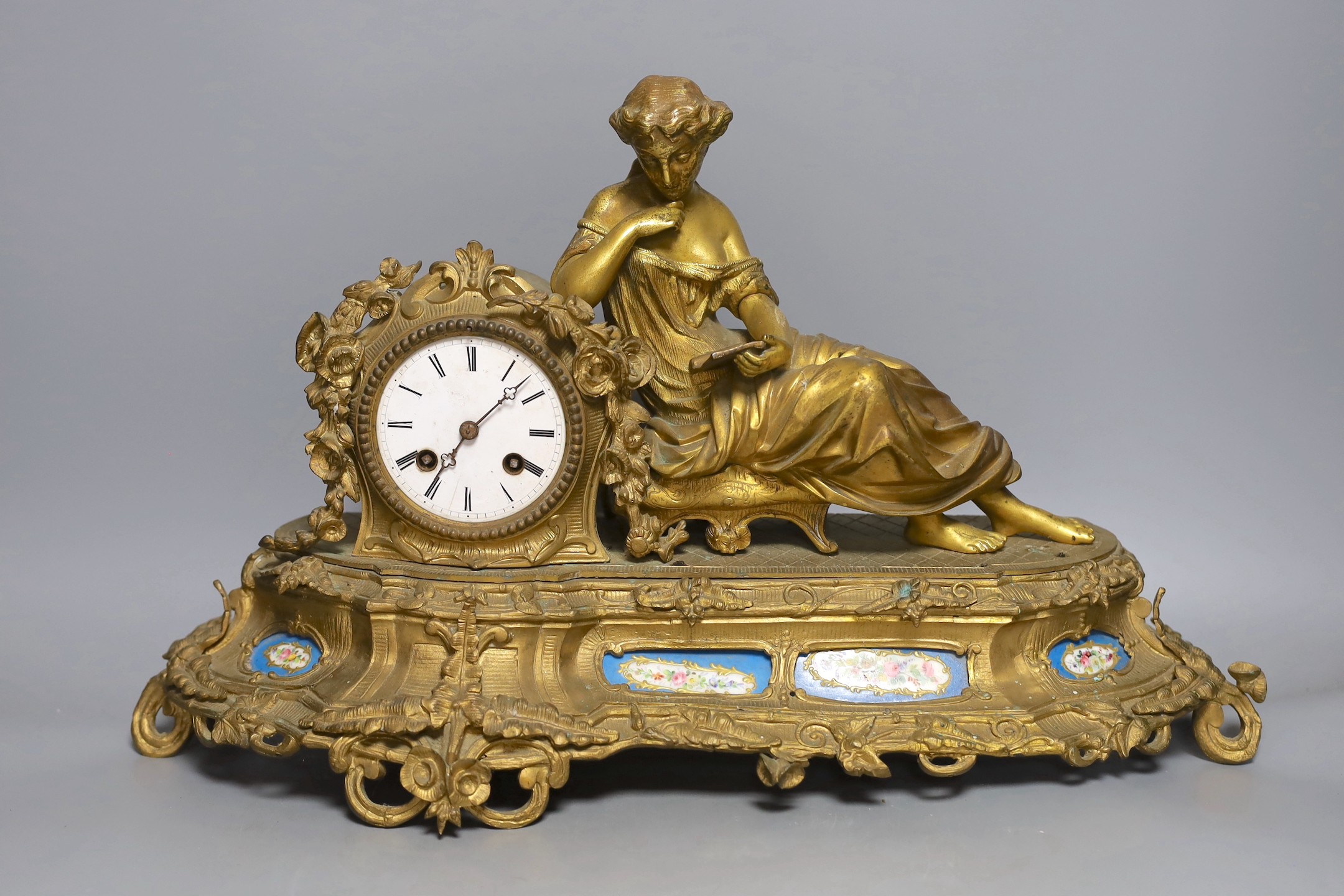 A French gilt metal mantel clock with blue enamel floral decoration and mounted lady reading - 47cm long